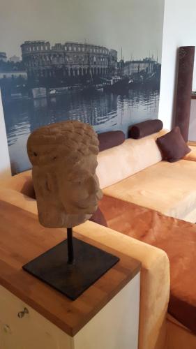 a statue of a head on a table next to two beds at Lili's House in Ližnjan