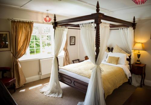 a bedroom with a canopy bed and a window at Claverton Hotel in Battle