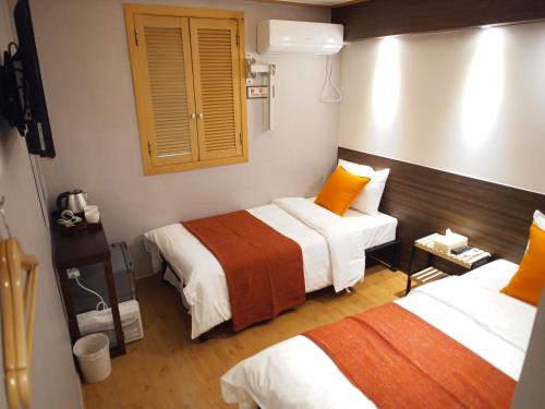 a hotel room with two beds with orange pillows at Hotel Park Hill Myeongdong in Seoul