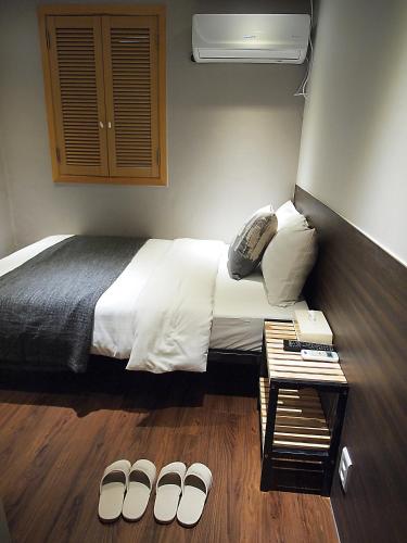a bedroom with a bed and a few pairs of slippers at Hotel Park Hill Myeongdong in Seoul