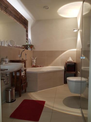 a bathroom with a tub and a toilet and a sink at Landlust am See in Schwangau