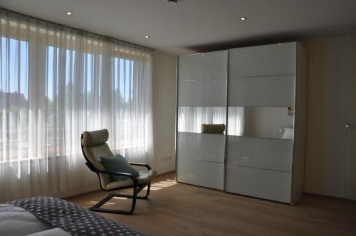 1 dormitorio con silla y armario grande en Ferienwohnung Fischbach, en Friedrichshafen