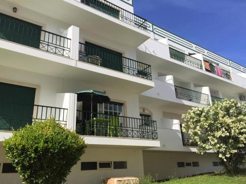 ein weißes Apartmenthaus mit Balkonen und Bäumen in der Unterkunft Sweet Home of Cabanas in Conceição