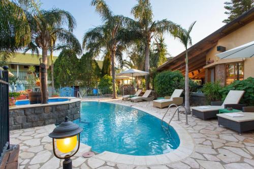 una piscina en un patio con palmeras en Out of Africa Resort, en Had Nes