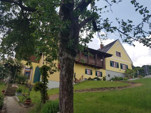 a yellow house with a tree in front of it at FerienAppartments Landhaus FühlDichWohl in Fehring