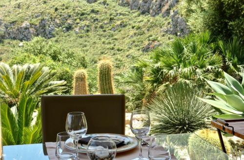 a table with wine glasses and a view of cactus at Baglio La Porta by Geocharme in San Vito lo Capo