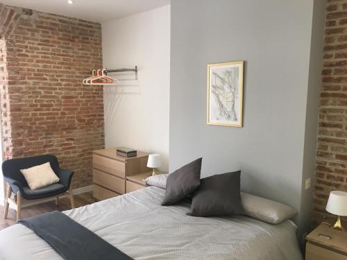 a bedroom with a bed and a brick wall at AIRVA: Apartamento Teresa Gil in Valladolid