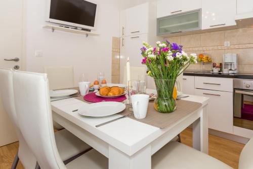 a white kitchen with a table with flowers in a vase at Ante Apartments in Podstrana