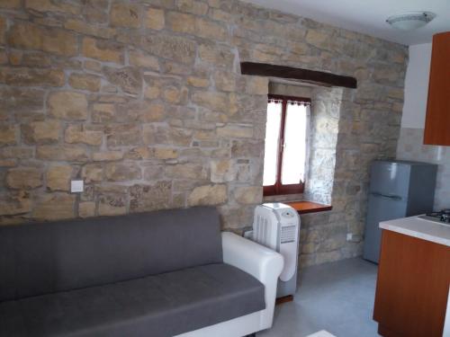 salon z kanapą i kamienną ścianą w obiekcie Apartmani Damiani w mieście Grožnjan