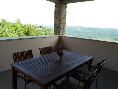 a wooden table and chairs on a balcony with a view at Apartmani Damiani in Grožnjan