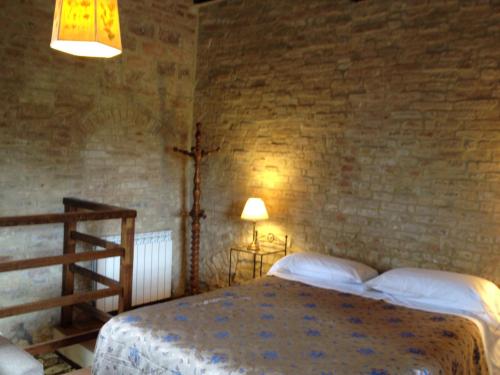 a bedroom with a bed and a brick wall at Fattoria Di Cavaglioni in San Rocco a Pilli
