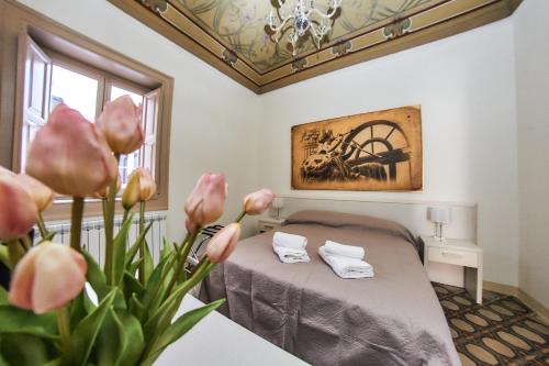 パレルモにあるSolemar Sicilia - Monacò roomsのベッドルーム1室(ピンクの花が飾られたベッド1台付)