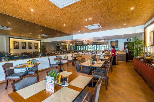 ein Restaurant mit Holztischen und -stühlen und einer Bar in der Unterkunft Le Patta Hotel Chiang Rai SHA Extra Plus in Chiang Rai