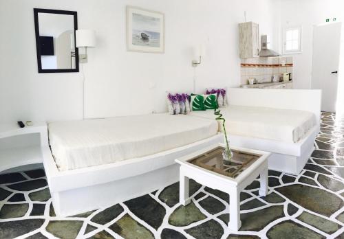 a white living room with two white beds and a table at Onar studios & residences in Pisses