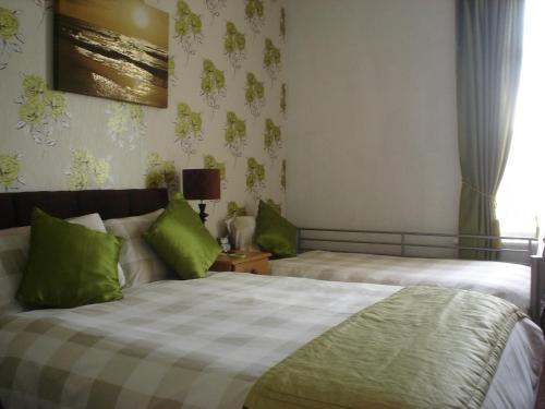 a bedroom with two beds with green pillows at The Franklyn Hotel B&B in Blackpool
