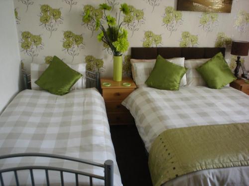 a bedroom with two beds with green pillows at The Franklyn Hotel B&B in Blackpool