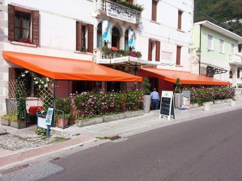 un restaurante con sombrillas naranjas al lado de una calle en Ristorante Pizzeria al Mondo, en Valstagna