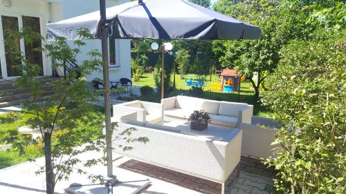 an umbrella and two white couches in a yard at Guest House Giorgi in Makhinjauri