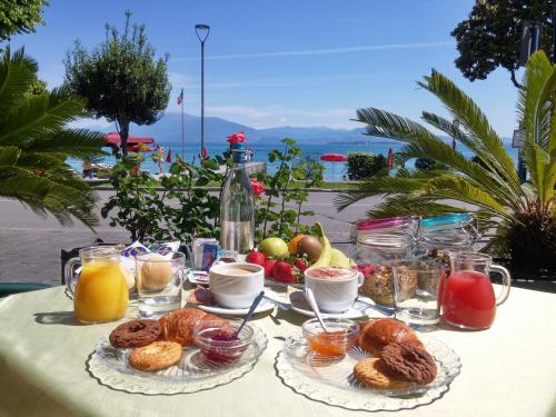 a table with breakfast foods and drinks on it at Hotel Riviera in Desenzano del Garda