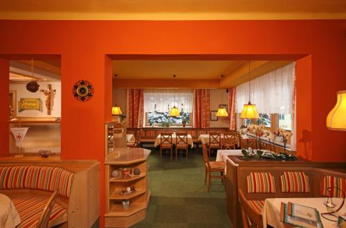 a restaurant with orange walls and tables and chairs at Alpengasthof Grimmingblick in Planneralm