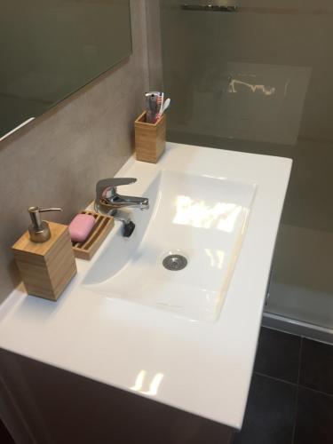 a white bathroom sink with a faucet and a mirror at Tiagos Apartament in Faro