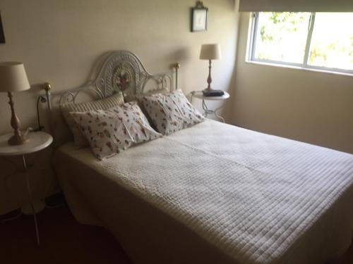 a bedroom with a white bed with pillows and a window at Tiagos Apartament in Faro