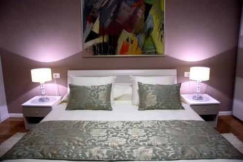 1 dormitorio con 1 cama con 2 lámparas y 1 pintura en Apartment Akvarel en Split