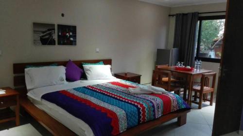 a bedroom with a bed with a colorful blanket on it at Ossanzaia Bilene Lodge in Vila Praia Do Bilene