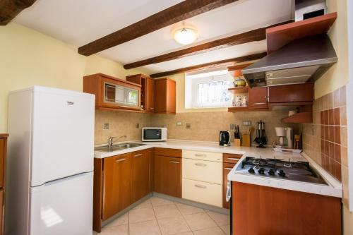 cocina con armarios de madera y nevera blanca en Villa Melita, en Opatija