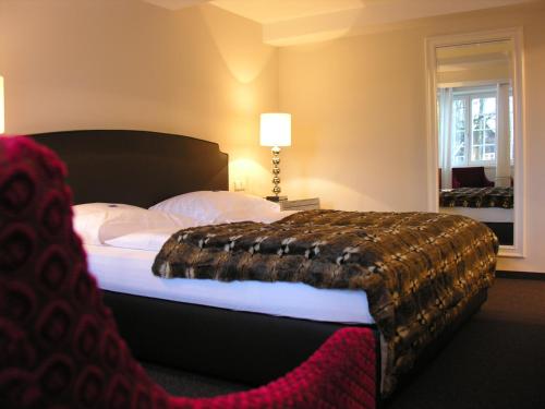 a bedroom with a large bed with a blanket on it at Hotel am Doktorplatz in Rheda-Wiedenbrück