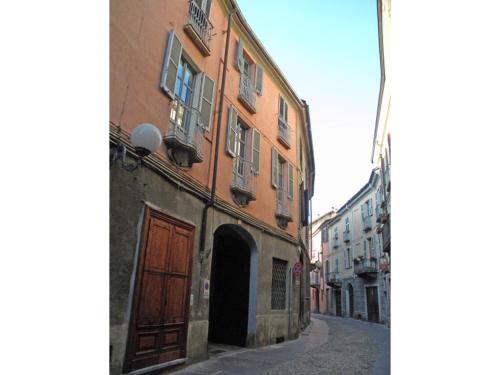 an alley with a building with a brown door and a street at Appartamento in centro storico in Asti