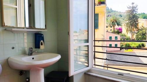 La salle de bains est pourvue d'un lavabo et d'une fenêtre avec vue. dans l'établissement Ospitalia del Mare Hostel, à Levanto