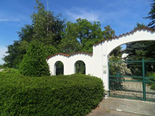 a gate to a white house with a hedge at Cuore Verde in Cavour