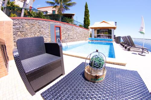 a chair and a potted plant next to a pool at Casa da Rainha Bungallow in Estreito da Calheta