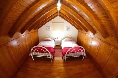 two beds in a small room with wooden walls at Casa da Rainha Bungallow in Estreito da Calheta