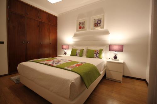 a bedroom with a large bed and two lamps at Apartamentos Gaivota Holidays in Nazaré