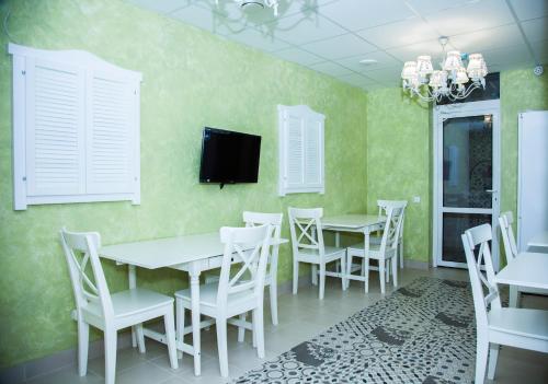 a dining room with white tables and chairs and a tv at Khosta Garden Hotel in Khosta