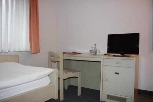 a bedroom with a desk with a television and a bed at Hotel Blume Post in Albstadt