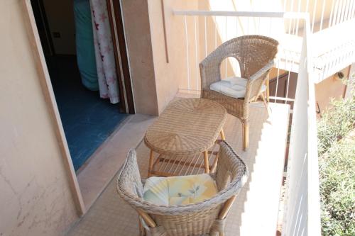 balcón con sillas, mesa y espejo en Poggio del sole, en Laigueglia