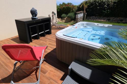 un bain à remous sur une terrasse avec une chaise et une télévision dans l'établissement Le Flamingo, à Villeneuve-lès-Maguelone