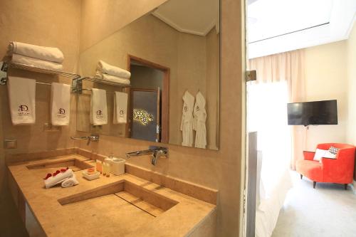 a bathroom with a sink and a red chair at Palais d'hôtes Darsor in Marrakech