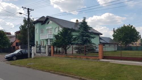 a house with a fence and a car in front of it at Guest House Luxotel in Zrenjanin