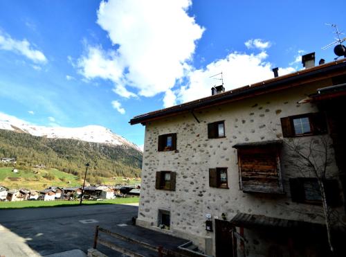 a stone building with a snow covered mountain in the background at Mountain Chalet Milly in Livigno