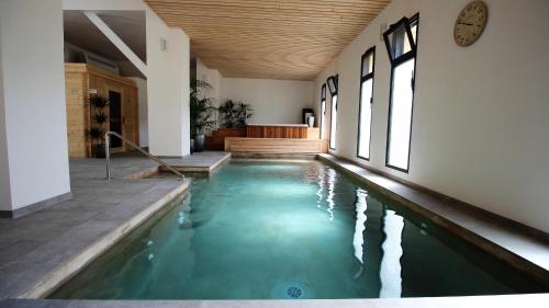 a swimming pool in a house with a clock on the wall at Clos Saint-Michel Resort & Spa in Malaucène