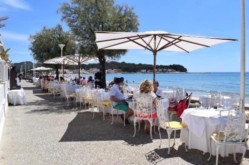 un groupe de personnes assises à des tables sous un parasol sur la plage dans l'établissement Grand Balaguier, à La Seyne-sur-Mer