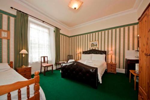 Habitación de hotel con cama y alfombra verde en Ashurst Lodge, en Torquay