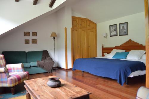 Un dormitorio con una cama, un sofá y una mesa. en Hotel El Jisu, en Camaleño