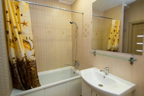 La salle de bains est pourvue d'un lavabo, d'une baignoire et d'un miroir. dans l'établissement VIP Apartment on Shishkarevskaya, à Soumy