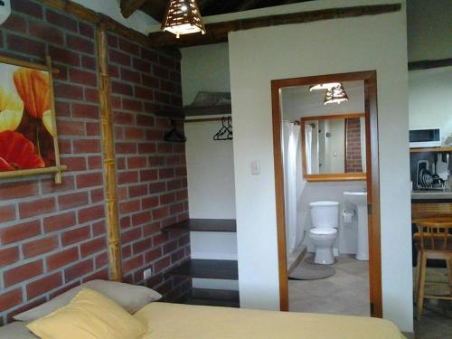 een slaapkamer met een bakstenen muur en een bed in een kamer bij Las Cabañas in Olón