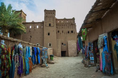 an alley in front of a castle with a bunch of clothes at La Baraka Auberge in Aït Ben Haddou